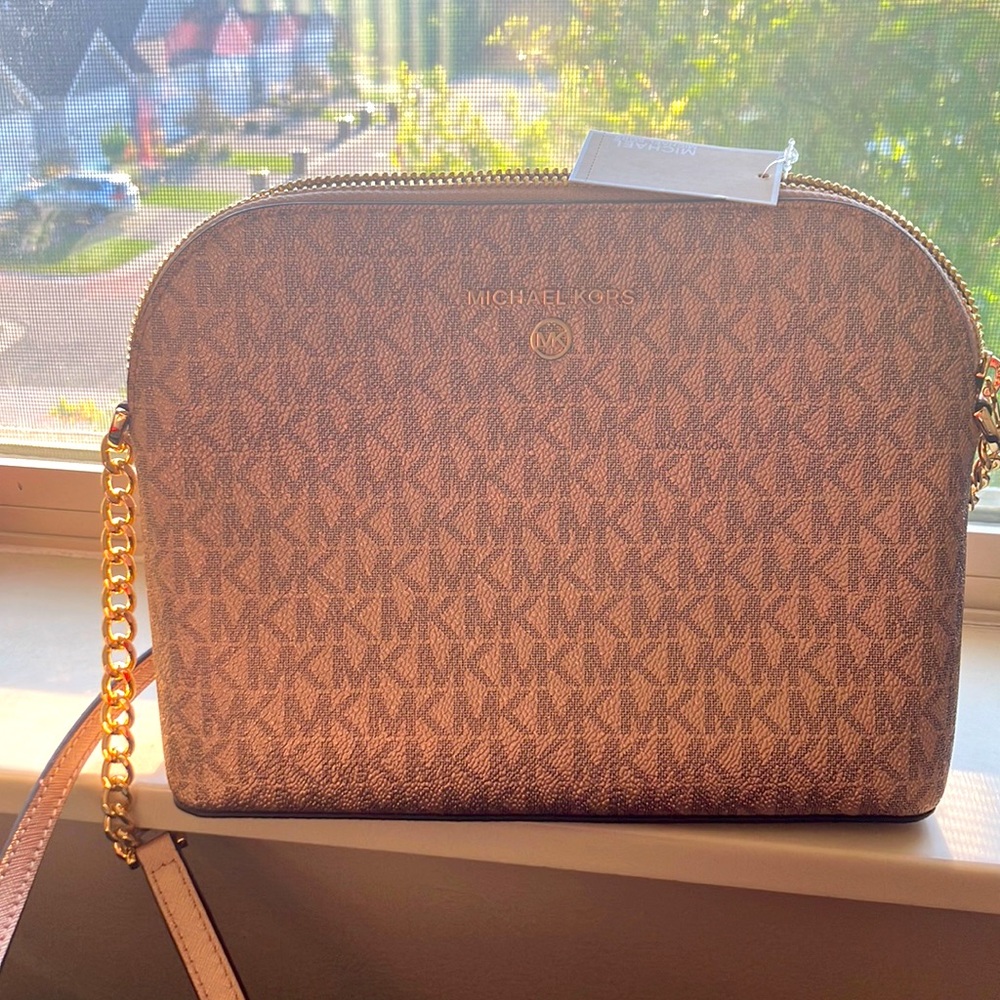 This bag is Michael kors and is rose gold pink with a gold strap.